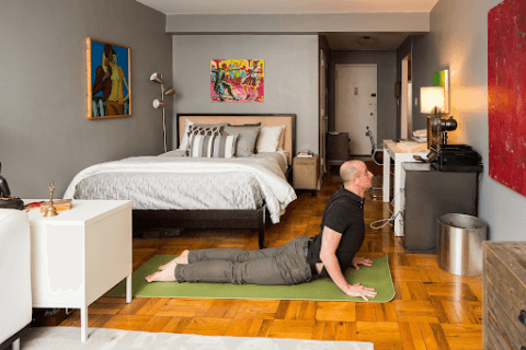 man performing yoga at home in personal yoga room with decor showing home yoga ideas